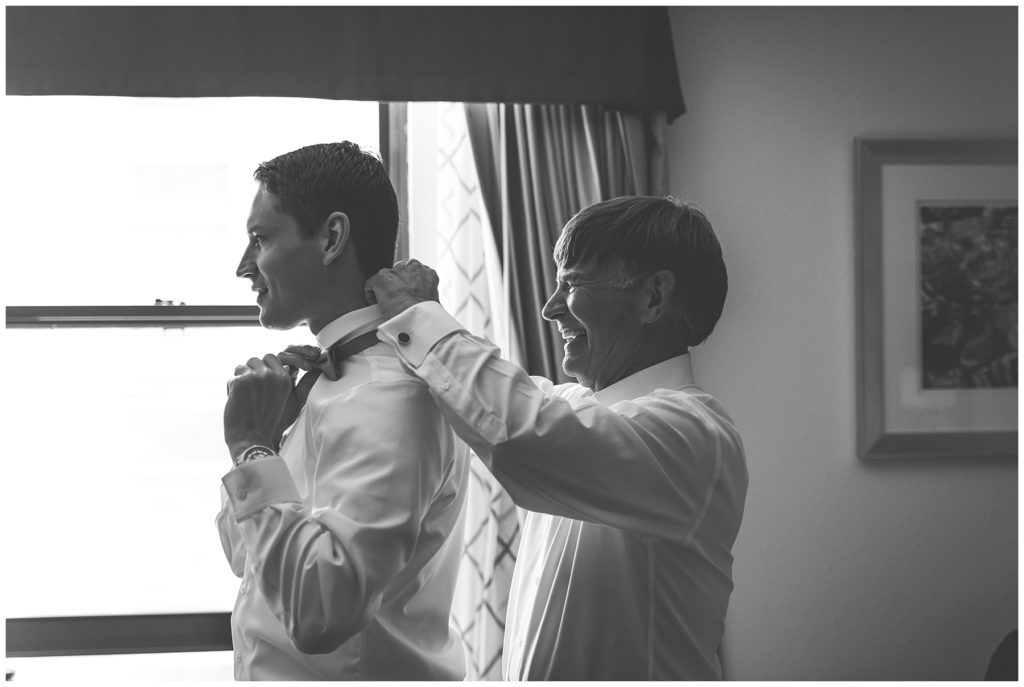 Father of bride helping the groom to tie his bow tie on his wedding day in Milwaukee