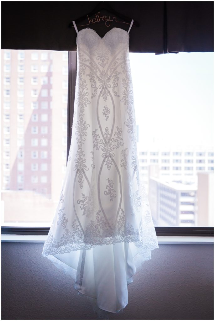 Milwaukee bride's white lace wedding dress hanging from a windowsill on a custom hanger